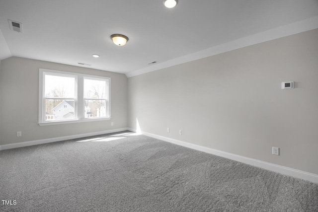 empty room featuring visible vents, carpet floors, baseboards, and vaulted ceiling