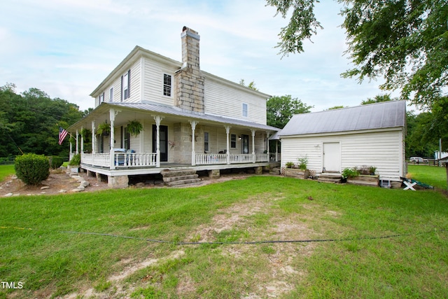 rear view of house with a chimney, metal roof, a lawn, and an outbuilding