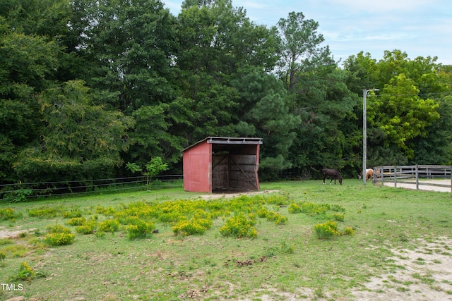 view of yard featuring a pole building, a rural view, fence, and an outdoor structure