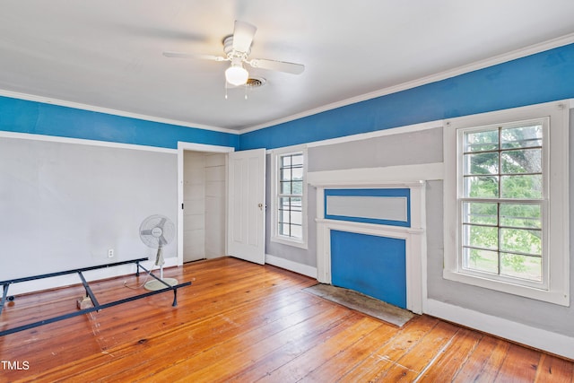 interior space with multiple windows, crown molding, light wood-style flooring, and baseboards