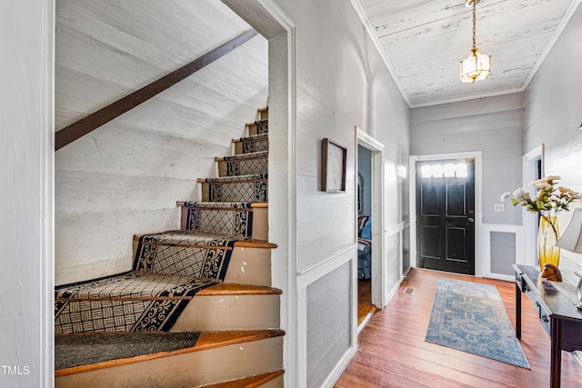 entrance foyer featuring crown molding, visible vents, stairway, wood finished floors, and wooden ceiling