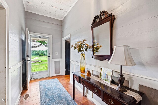 entryway with light wood-type flooring, ornamental molding, and a wealth of natural light