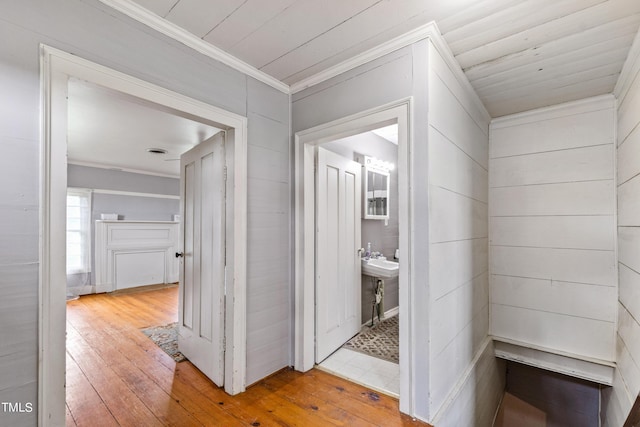 hallway featuring light wood-type flooring, wooden ceiling, and crown molding