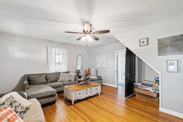 living room featuring wood finished floors, a ceiling fan, and baseboards