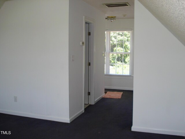 corridor with a textured ceiling, carpet floors, and lofted ceiling