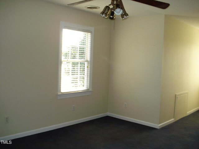 spare room with dark carpet and ceiling fan