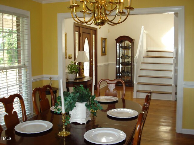 dining area with hardwood / wood-style flooring, a chandelier, and crown molding