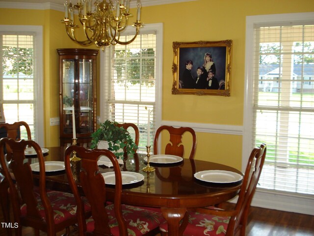 dining space featuring wood-type flooring, an inviting chandelier, and crown molding