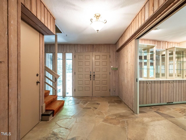 interior space with wooden walls and a textured ceiling