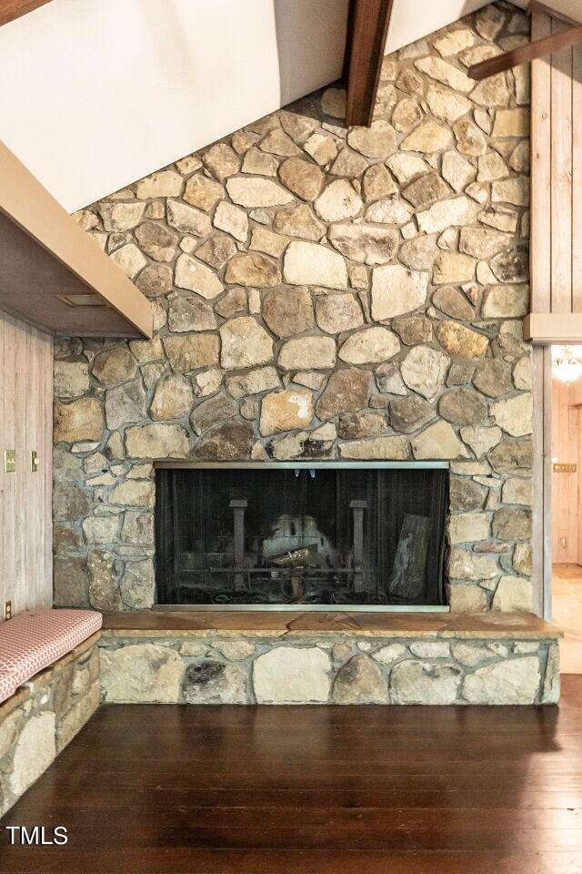 details featuring wood-type flooring, beam ceiling, wooden walls, and a stone fireplace