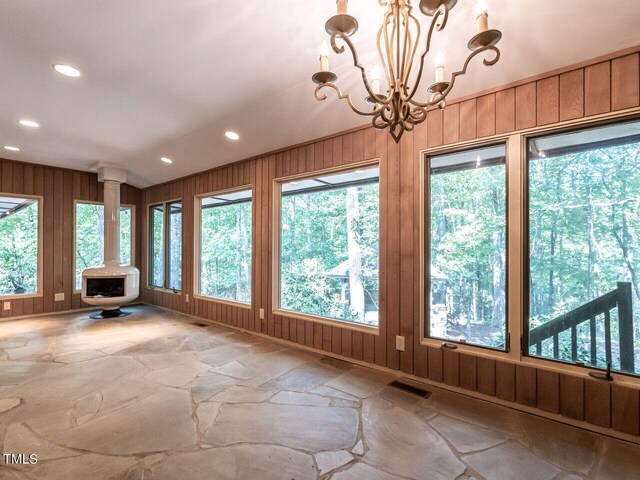 unfurnished sunroom with a wood stove and an inviting chandelier