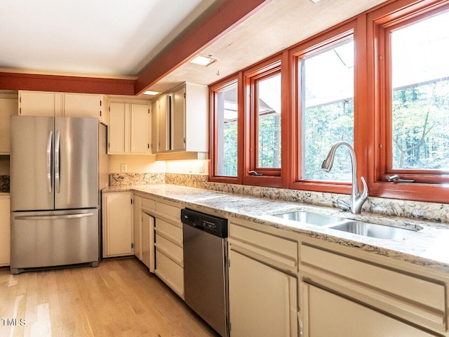 kitchen featuring light hardwood / wood-style flooring, sink, light stone countertops, cream cabinets, and appliances with stainless steel finishes