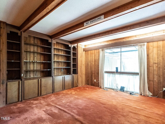 carpeted empty room with beamed ceiling and built in shelves