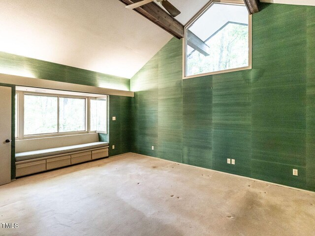 unfurnished room featuring plenty of natural light, beamed ceiling, and carpet floors