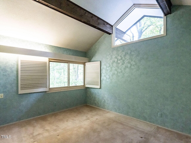 carpeted spare room with plenty of natural light and lofted ceiling with beams