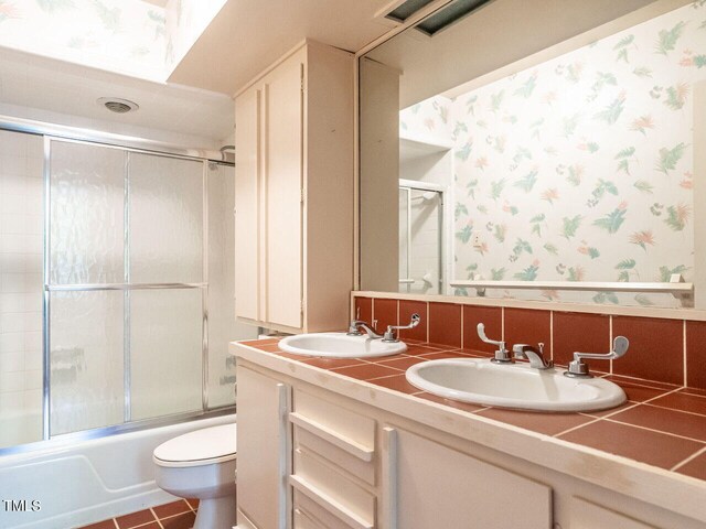 full bathroom featuring tile patterned floors, toilet, bath / shower combo with glass door, and vanity