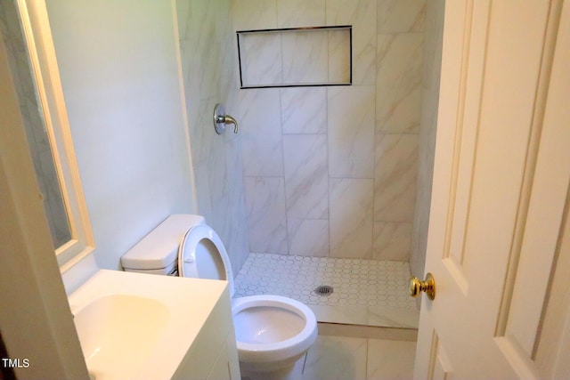 bathroom with vanity, a tile shower, and toilet