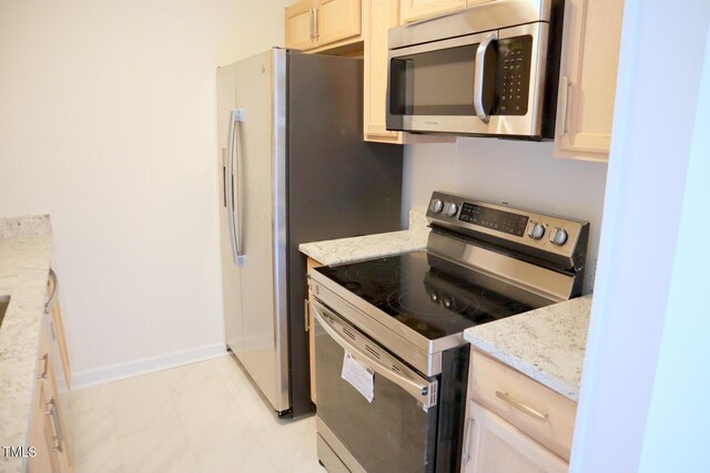 kitchen with appliances with stainless steel finishes, light tile patterned floors, light brown cabinetry, and light stone countertops