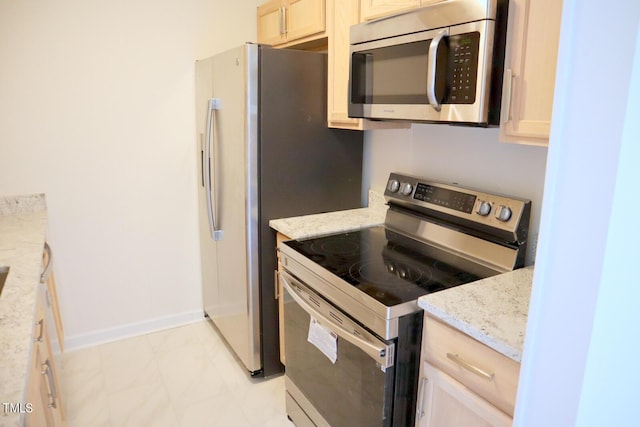 kitchen with appliances with stainless steel finishes, light stone counters, and light brown cabinets