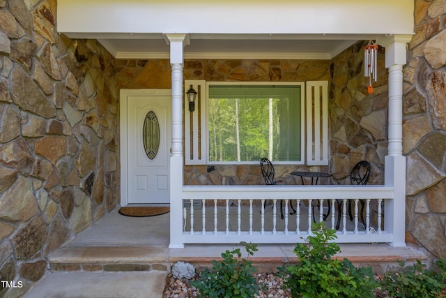 doorway to property featuring a porch and stone siding