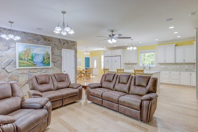 living area featuring recessed lighting, light wood-style floors, ornamental molding, and ceiling fan with notable chandelier