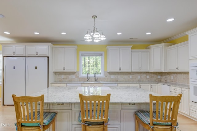 kitchen featuring white cabinets, a center island, freestanding refrigerator, and a sink