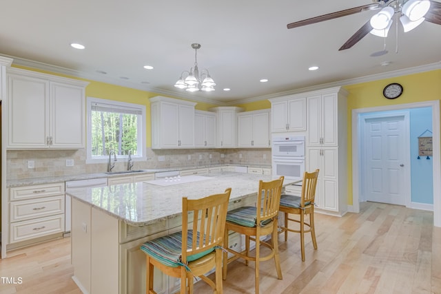 kitchen with light wood-style flooring, a sink, white double oven, white cabinetry, and crown molding