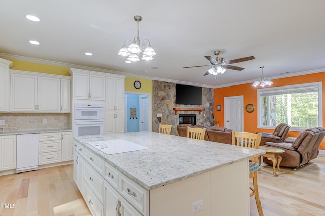 kitchen with double oven, a fireplace, open floor plan, and ornamental molding