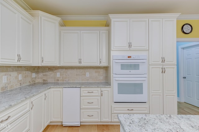 kitchen with decorative backsplash, double oven, crown molding, and light stone countertops