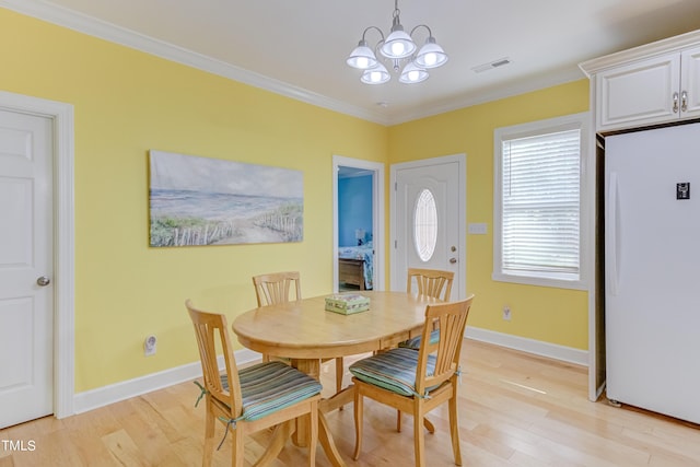 dining area featuring visible vents, light wood-style floors, an inviting chandelier, and ornamental molding