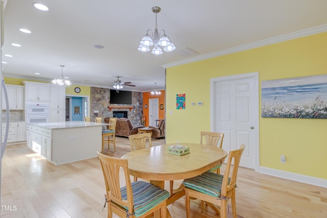 dining room with light wood-type flooring, baseboards, ornamental molding, and a fireplace