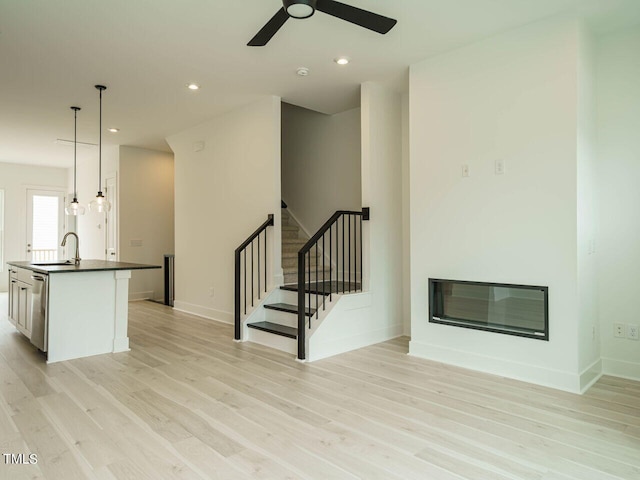 unfurnished living room with sink, ceiling fan, and light hardwood / wood-style floors