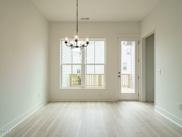 unfurnished dining area featuring light hardwood / wood-style flooring and an inviting chandelier