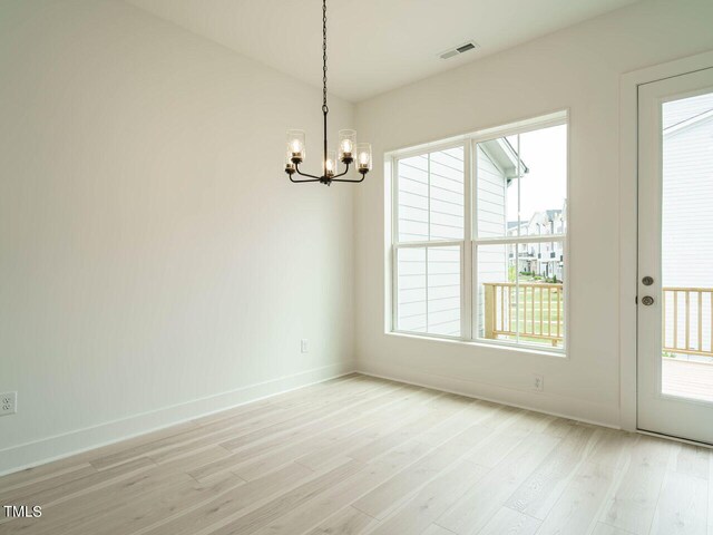 unfurnished dining area featuring a notable chandelier and light hardwood / wood-style flooring