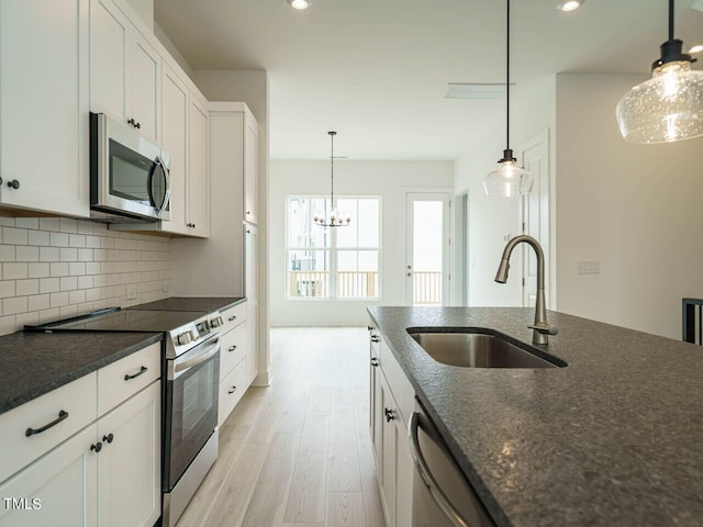 kitchen featuring white cabinetry, light hardwood / wood-style floors, appliances with stainless steel finishes, decorative backsplash, and sink