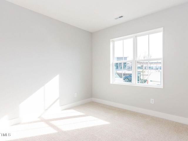 empty room featuring carpet, visible vents, and baseboards