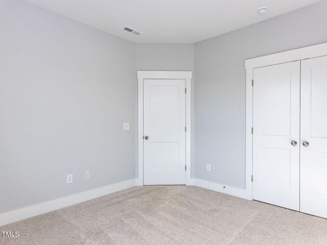 unfurnished bedroom with baseboards, carpet, visible vents, and a closet