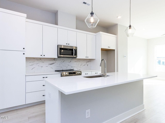 kitchen with stainless steel appliances, a sink, visible vents, and decorative backsplash