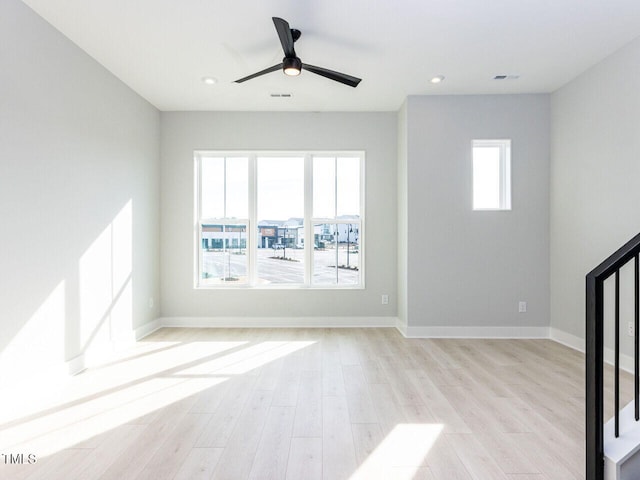 unfurnished room with ceiling fan, visible vents, baseboards, stairs, and light wood-style floors