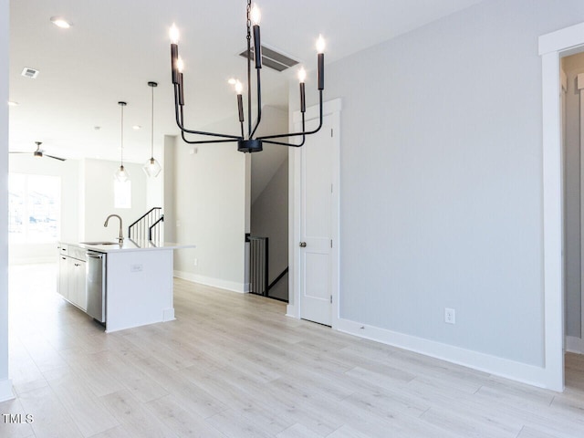 kitchen with visible vents, stainless steel dishwasher, light wood-style floors, a kitchen island with sink, and a sink