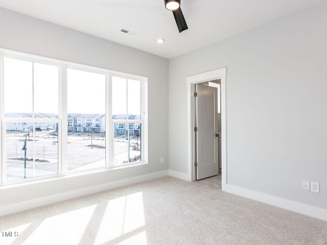 empty room featuring carpet floors, recessed lighting, a ceiling fan, a residential view, and baseboards