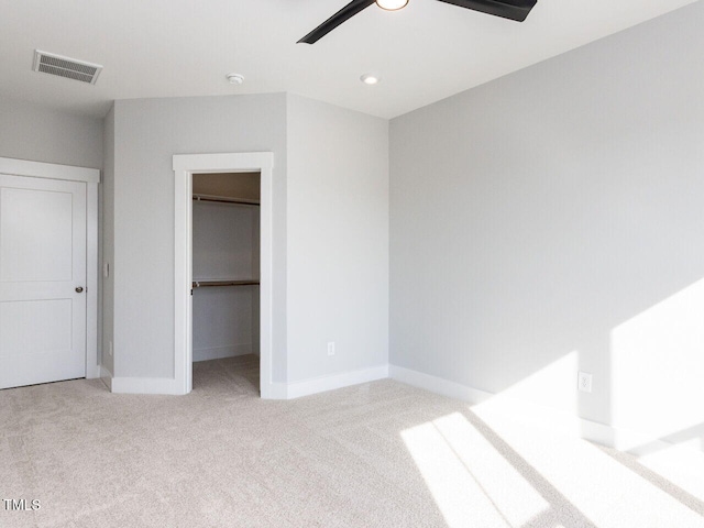 unfurnished bedroom with carpet floors, baseboards, visible vents, and a walk in closet