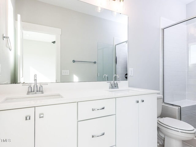 full bathroom with a tile shower, double vanity, a sink, and toilet