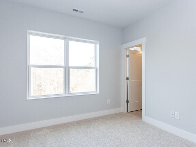 spare room featuring carpet floors, visible vents, and baseboards