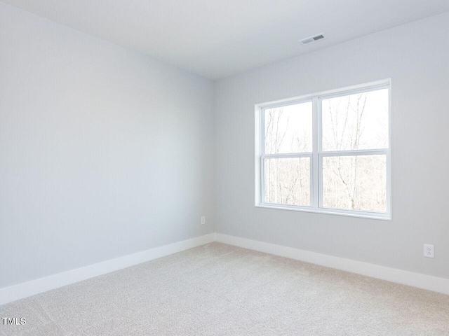 spare room with carpet floors, baseboards, and visible vents