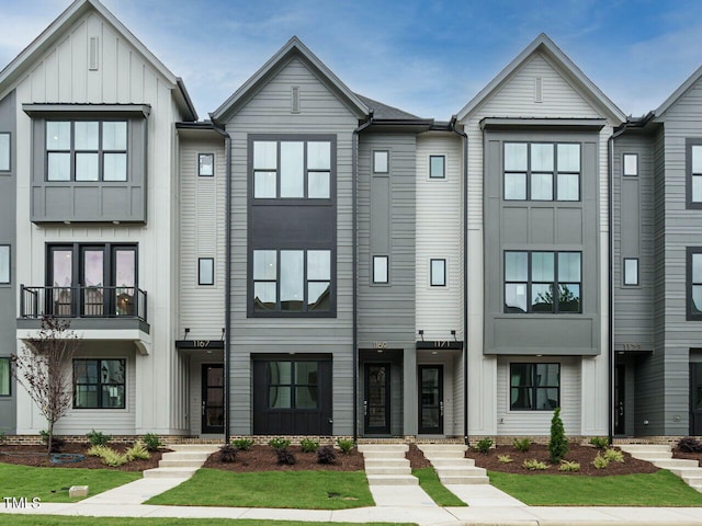 townhome / multi-family property with board and batten siding and a front yard