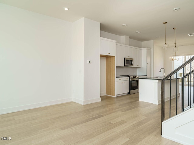 kitchen with decorative backsplash, dark countertops, appliances with stainless steel finishes, light wood-style floors, and white cabinetry