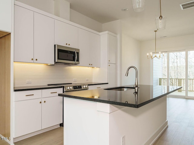 kitchen with appliances with stainless steel finishes, dark countertops, visible vents, and a sink