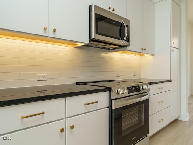 kitchen with white cabinetry, appliances with stainless steel finishes, light wood-style flooring, and backsplash