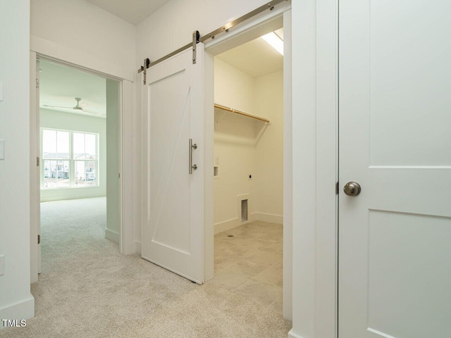 interior space featuring light carpet, laundry area, a barn door, baseboards, and washer hookup